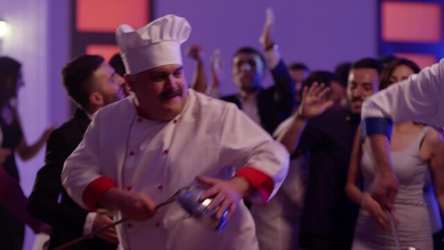 Cook dancers having fun dancing at a colorful party . Funny cook chef in white uniform, with a hat and ladle , smiling and partying during party . Shot on RED EPIC Cinema Camera 