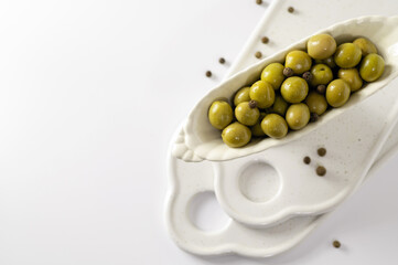 green olives in decorative dishes on white background, top view, empty space for text