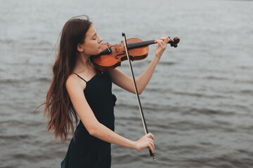 a girl of Asian appearance plays the violin in nature