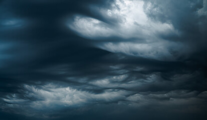 Photograph of a dramatic isolated Asperitas cumulus thunderstorm cloud as it swirls and moves...