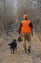 Hunter with ruffed grouse and Lab 