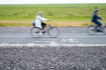 bike path by a green meadow with blurred cyclists concept for traffic turnaround