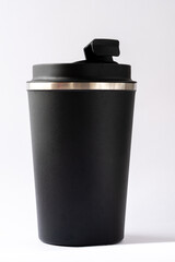 Black thermocup or thermos mug for tea or coffee against a white background. Top slightly opened, hot beverage