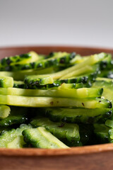 白い背景と木のボウルに盛り付けられたゴーヤの炒め物