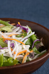 青い背景と木のボウルに盛り付けられたサラダ