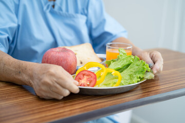 Asian senior or elderly old lady woman patient eating breakfast vegetable healthy food with hope and happy while sitting and hungry on bed in hospital.