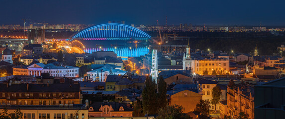 Evening view of the Podilskyi Bridge, the Dnieper River and the Ferris Wheel at Kontraktova Square, Kyiv, Ukraine.