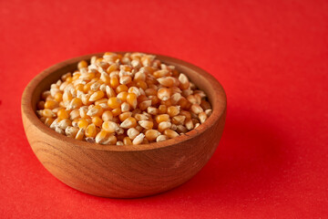 Field Corn in wooden bowl on red background popcorn