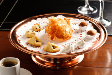 Set of delicious biscuits of different types and sweets, on a plate on top of a wooden table