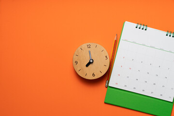 close up of calendar and clock on the orange table background, planning for business meeting or...