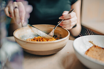 Italian food. woman hand holding fork and knife with spaghetti bolognese sauce in bowl