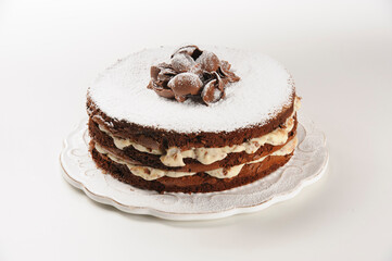 Tasty chocolate naked cake with cream filling, sprinkled baking sugar and chocolate curls on top, isolated