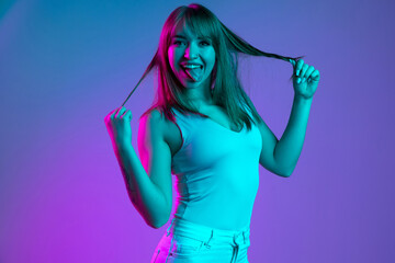 Naklejka premium One young beautiful girl having fun isolated on blue studio background in neon light filter. Concept of human emotions, facial expression, youth, sales, ad.