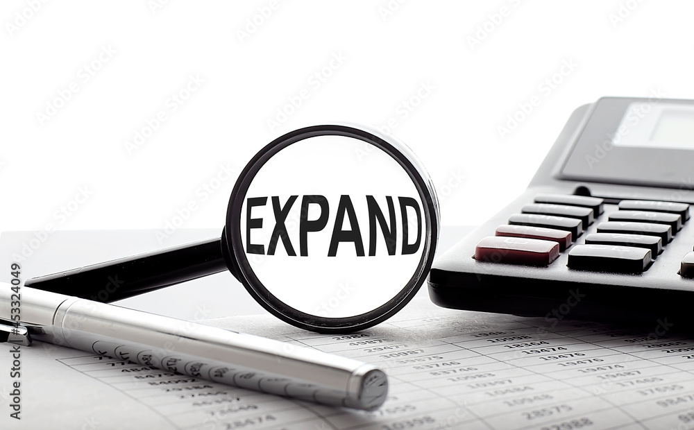 Aufkleber expand concept. magnifier glass with text on chart with pen and calculator