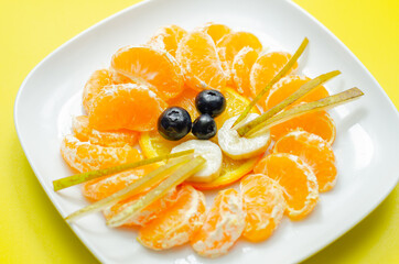 Fresh fruit orange, mandarin, banana, grape and pear served in a creative way, fruit snack in the shape of a lions head
