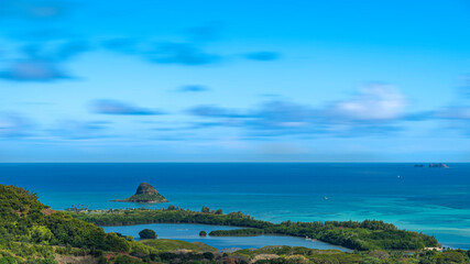 View of Mokoli'i island, Moku Manu and Moli'i Fishpond in O'ahu, Hawaii. Ancient fishing ponds of Hawaii surrounded by crystal clear blue ocean on a sunny day with some clouds in sky