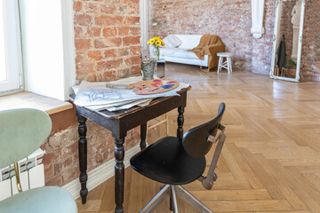 bright workshop room for the creation and work of an architect and artist in a loft style with brick walls and parquet. the walls are decorated with examples of stucco.