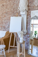bright workshop room for the creation and work of an architect and artist in a loft style with brick walls and parquet. the walls are decorated with examples of stucco.