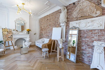 bright workshop room for the creation and work of an architect and artist in a loft style with brick walls and parquet. the walls are decorated with examples of stucco.