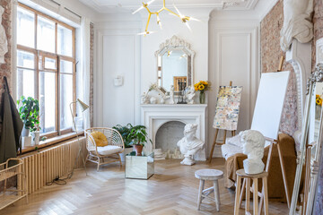 bright workshop room for the creation and work of an architect and artist in a loft style with brick walls and parquet. the walls are decorated with examples of stucco.