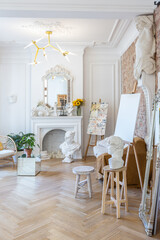 bright workshop room for the creation and work of an architect and artist in a loft style with brick walls and parquet. the walls are decorated with examples of stucco.
