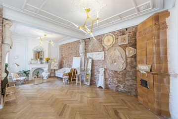 bright workshop room for the creation and work of an architect and artist in a loft style with brick walls and parquet. the walls are decorated with examples of stucco.