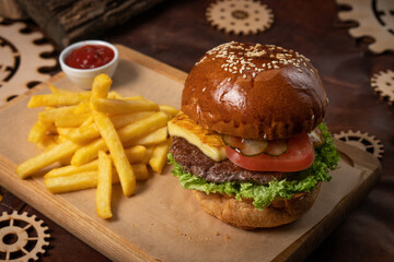 Beef burger are served with french fries on a decorative wooden board with tomato sauce with wooden decorative pieces of simple mechanism. Restaurant, Fast food concept. Street food concept. 