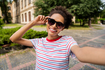 Photo of young cheerful african girl happy positive smile make selfie hand touch sunglass trip...