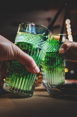 Two hands (male and female) clinking toasting with mojito cocktails in cafe or bar