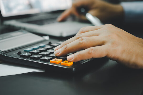 Closeup of a businessman's hand and a calculator.