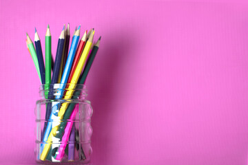 Colored pencils on glass on a pink background
