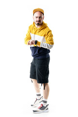 Frustrated urban hip hop style fashion man showing time on wristwatch. Late concept. Full length portrait isolated on white background