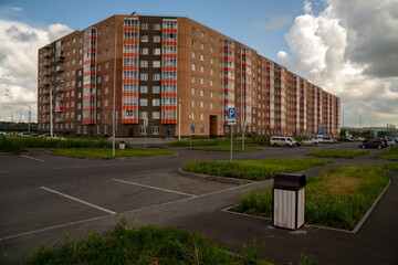 Residential apartment building and parked cars in a parking lot nearby in the new Yasny...