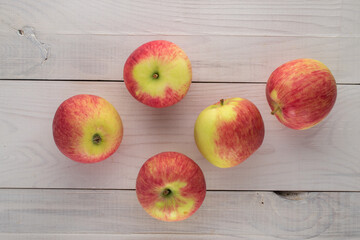 Several ripe apples on a wooden table, top view.