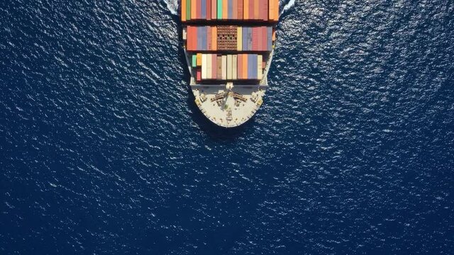High aerial top down view to a heavy loaded container cargo vessel traveling over blue sea