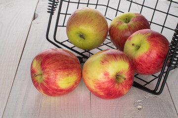Several ripe apples in a basket on a wooden table.