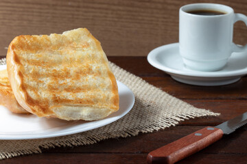 Toasted bread with butter and black coffee, selective focus.
