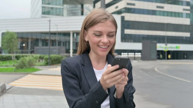 Young Businesswoman Celebrating on Smartphone while Walking on the Street