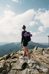 sporty young woman with a backpack on top of the mountain