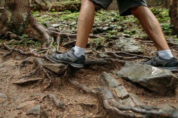 male feet in trekking boots walk in the woods