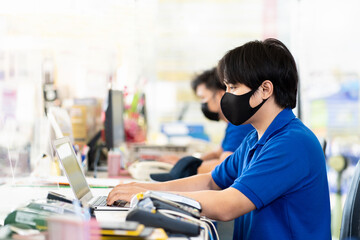 Group of Asian male office worker wearing protective medical face mask and working with computer desktop in auto car repair shop. Receptionist male. Male office worker. Male staff. Payment department