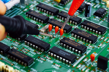 The hand of the engineer measures the voltage on the electrical board with the test leads of the multimeter. Closeup.	