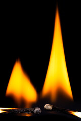 Two burning matchsticks against a black background