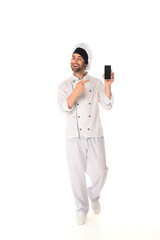 Smiling chef pointing at smartphone with blank screen on white background