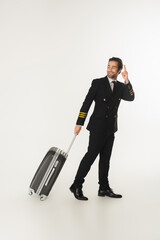 Smiling pilot with suitcase pointing with finger on white background © LIGHTFIELD STUDIOS