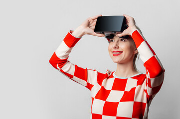 Beautiful woman with blond hair in in a 70s red square dress with VR glasses