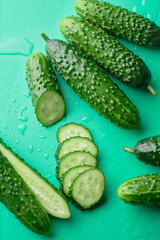 Set of fresh whole and sliced cucumbers on a green background with water drops. Garden cucumber wallpaper backdrop design