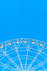white ferris wheel on a background of blue sky without clouds, copy space