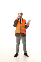 Smiling engineer holding digital tablet and talking on smartphone on white background
