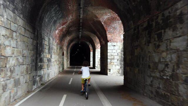 Italy, Spezia, Liguria - The new pedestrian walk , cycle path ( bicycle lane ) that connects Framura, Bonassola and Levanto passing through the ancient train tunnels - 7 years old child go bike